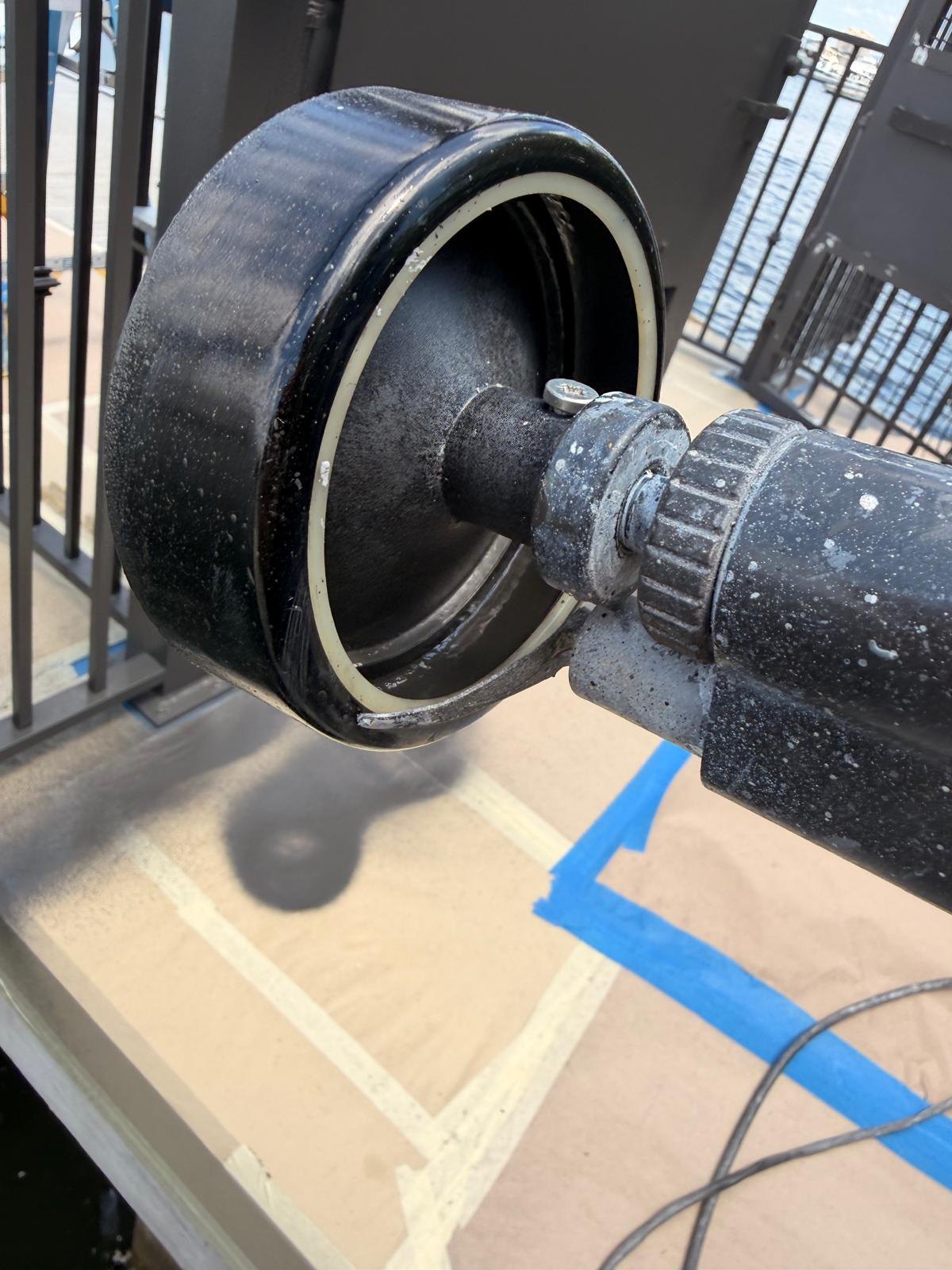 Close-up of an electrostatic spray gun applying coating to installed metal